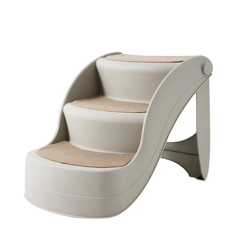 Foldable grey plastic pet stairs with non-slip mat placed next to a sofa for a small dog.