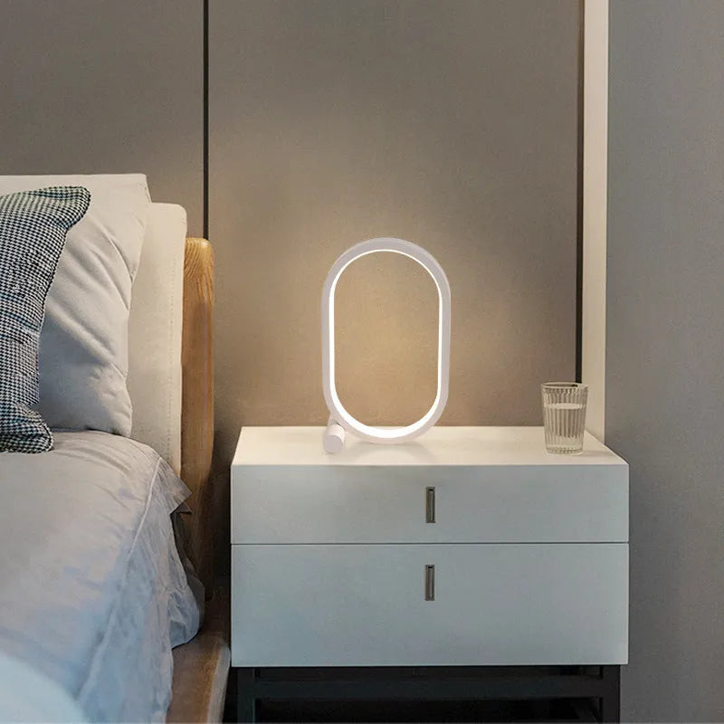 USB plug-in oval acrylic touch lamp with dimmable LED, metal body, on a bedside table