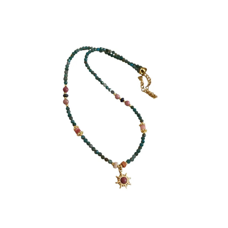 Freshwater pearl necklace with a blue stone sun pendant on an adjustable gold-toned chain.