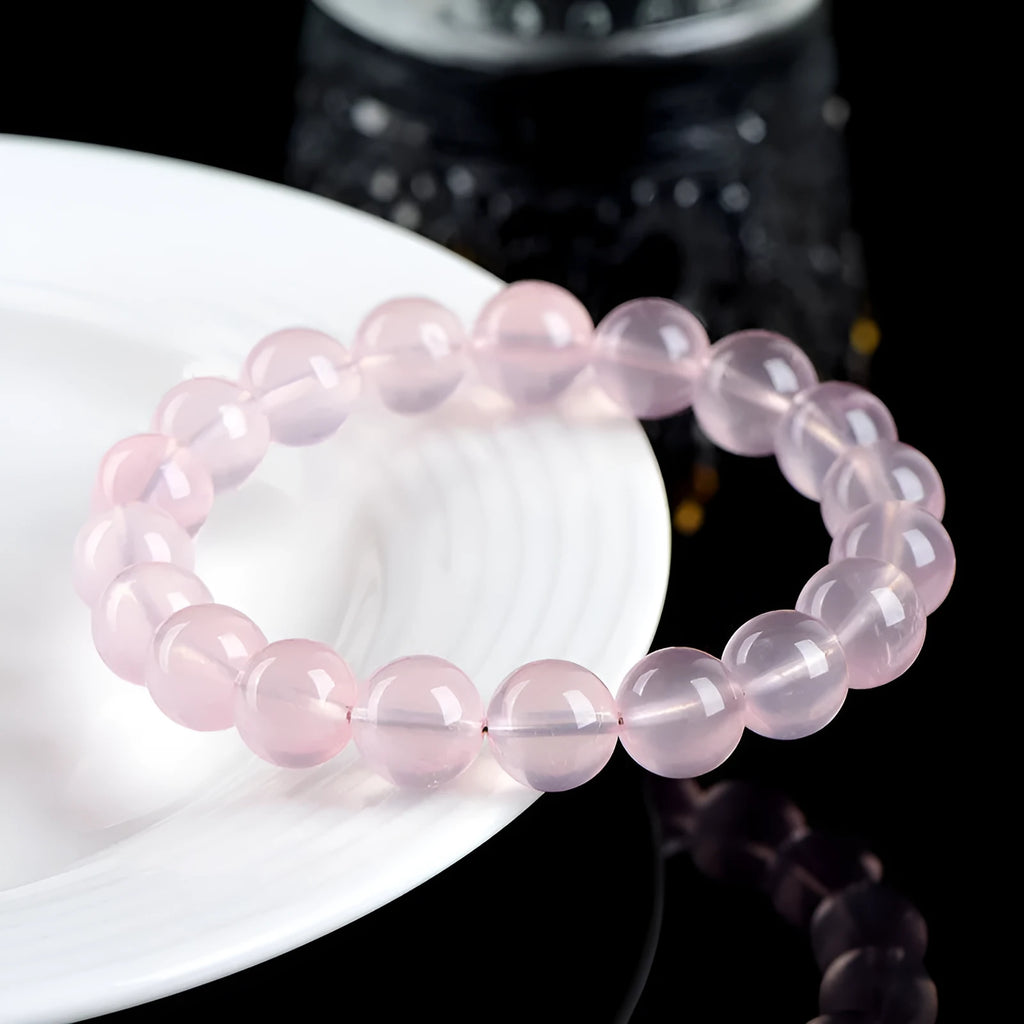 Natural starlight crystal round beads women's bracelet in pink on a wrist, showing polished single circle beads.