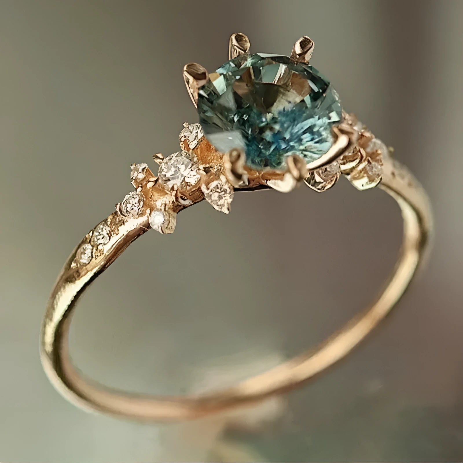 Gold plated geometric ring with a claw setting holding an inlaid zircon stone on a chamfered square pattern band.