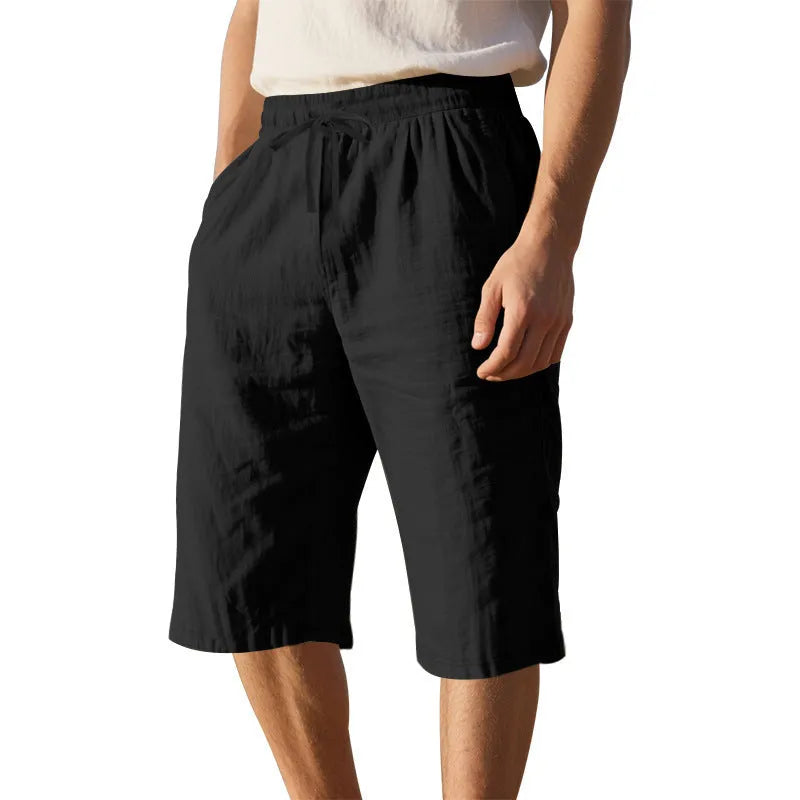 Man wearing loose, high-waisted linen shorts in a solid colour with a drawstring waist.