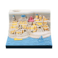 Assembled Santorini beach 3D paper model notepad with decorative lighting on a desk.
