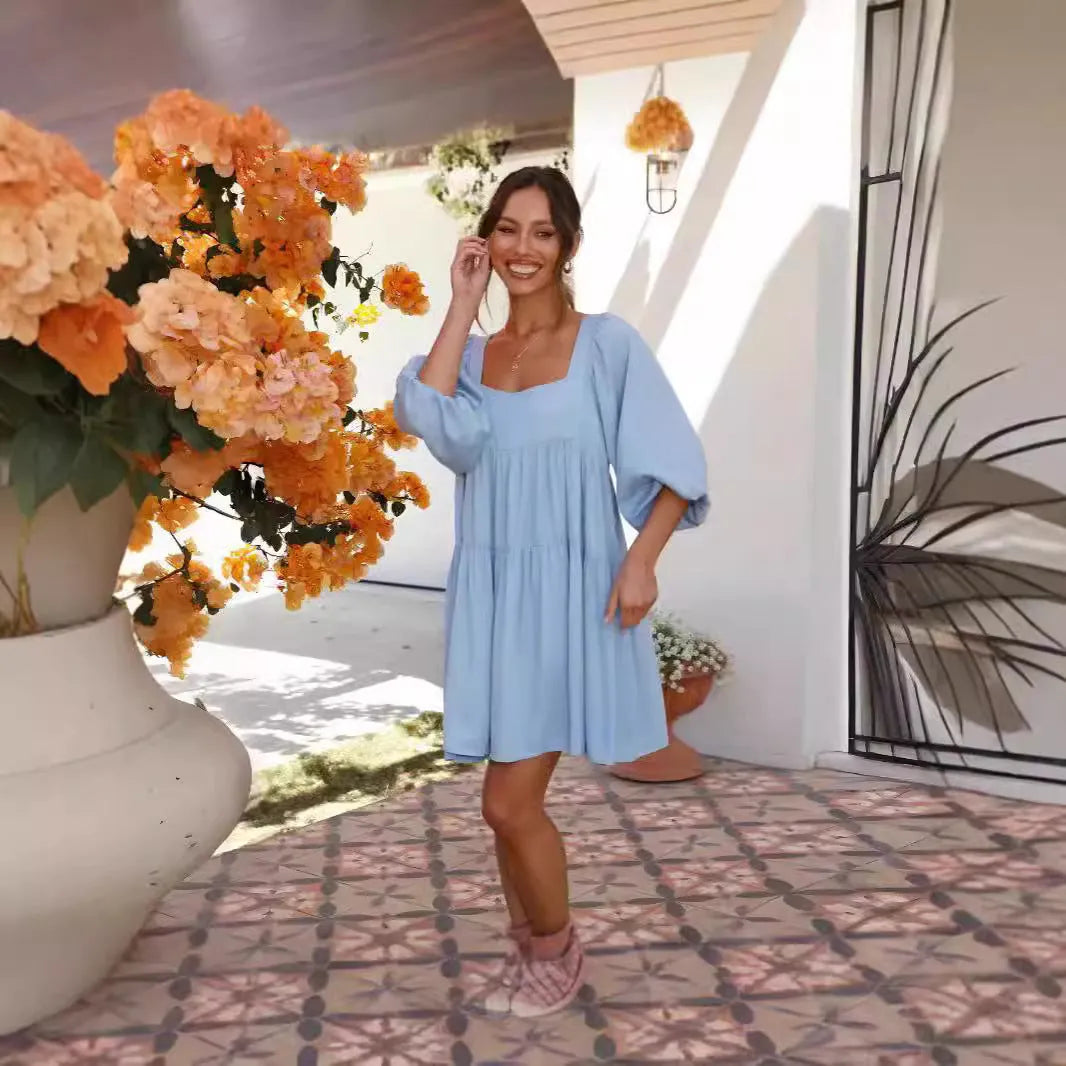 A light blue children's backless dress with a square collar, puff sleeves, and an A-line skirt on a hanger.