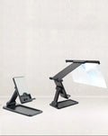 Black foldable mobile phone screen amplifier with a detachable phone holder on a desktop.