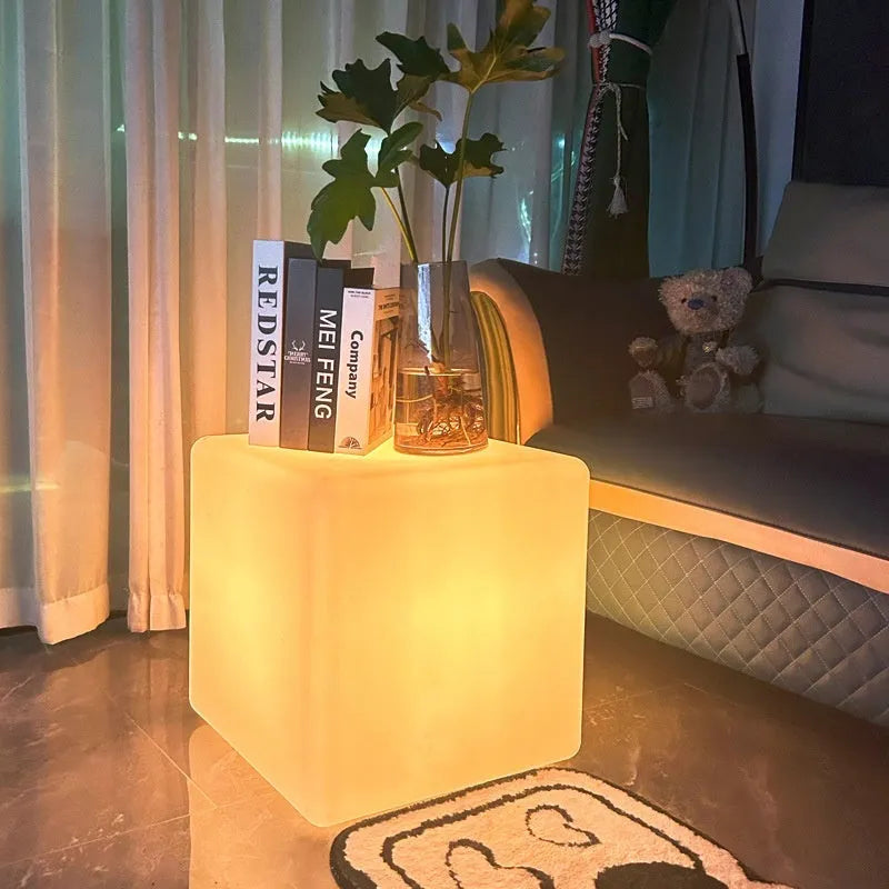 Modern square LED cube stool light outdoors, functioning as both a garden seat and a waterproof light source.