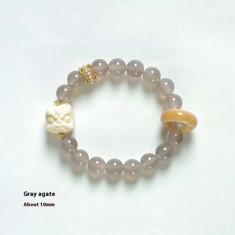 Hand-woven bracelet with 10mm round grey agate and mellite beads on a wrist.