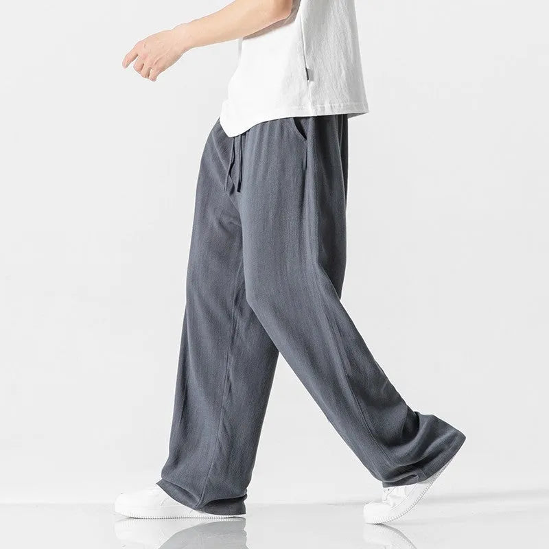 Man wearing beige loose-fit straight-leg cropped trousers with a drawstring waist.