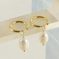 Geometric gold-coloured stainless steel earrings with a white pearl detail on a white background.