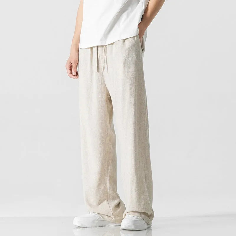 Man wearing beige loose-fit straight-leg cropped trousers with a drawstring waist.
