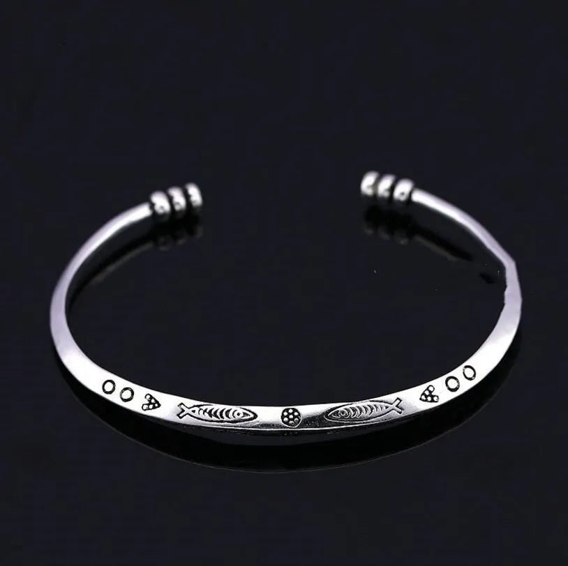 Close-up of a silver-toned women's bracelet with a detailed Chinese-style fish charm and an adjustable opening clasp.