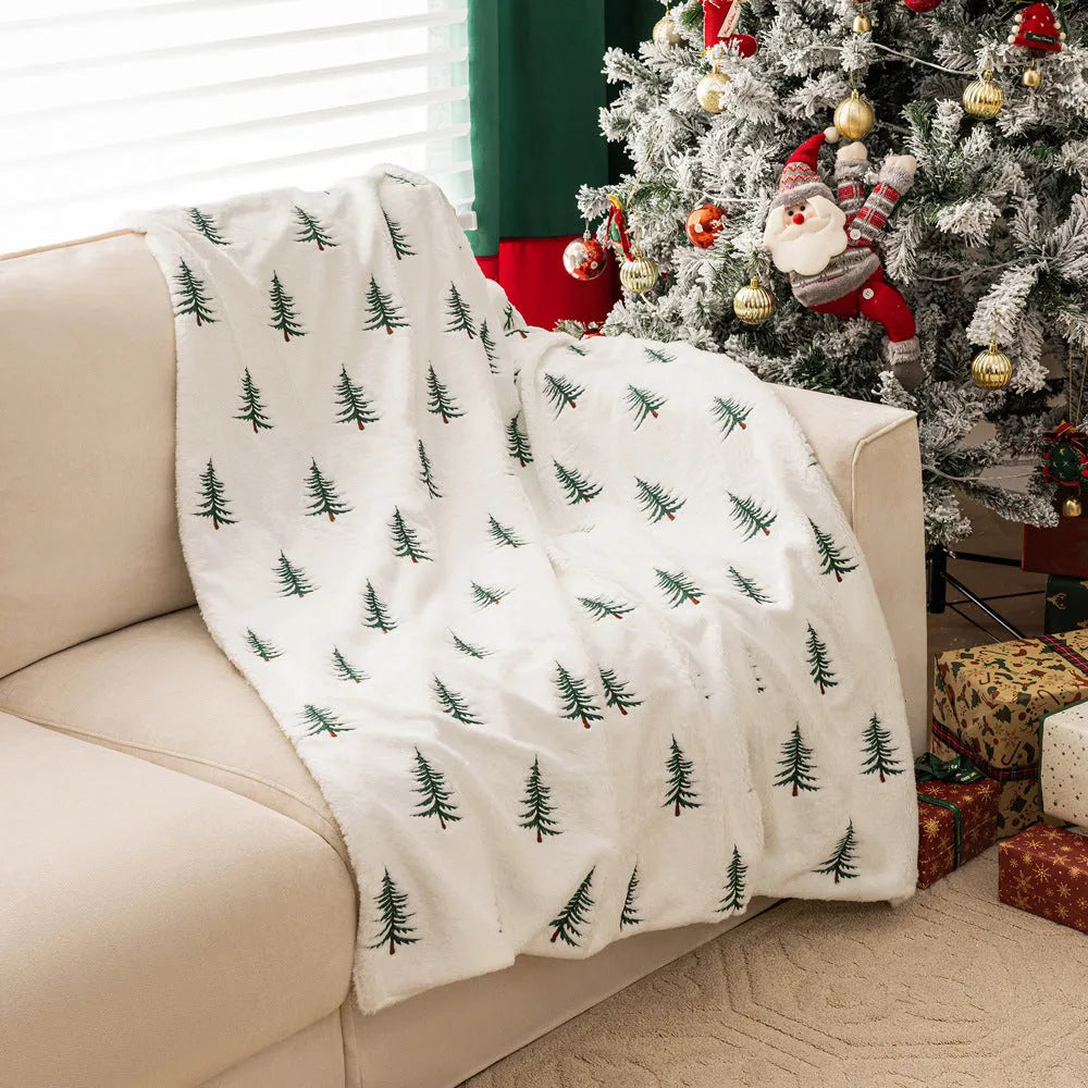 White Christmas plush sofa blanket with embroidered tree motif on a living room sofa