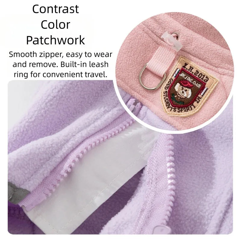 Small dog wearing a colour-block fleece jumpsuit in purple and pink, with full-zip front and leash ring