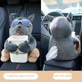 Plush car tissue box holder hanging from flip-down armrest with humorous dog design