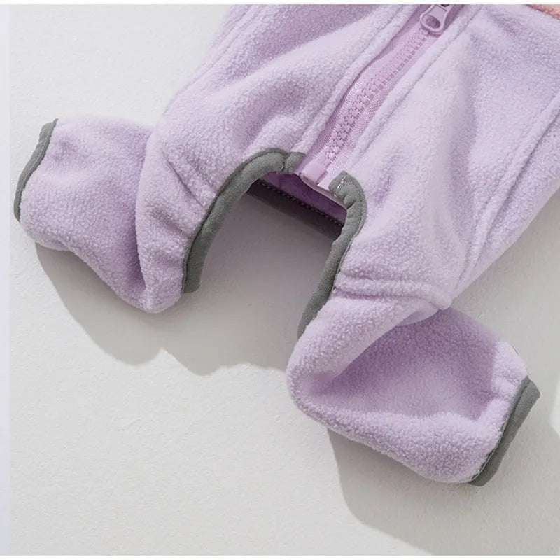 Small dog wearing a colour-block fleece jumpsuit in purple and pink, with full-zip front and leash ring