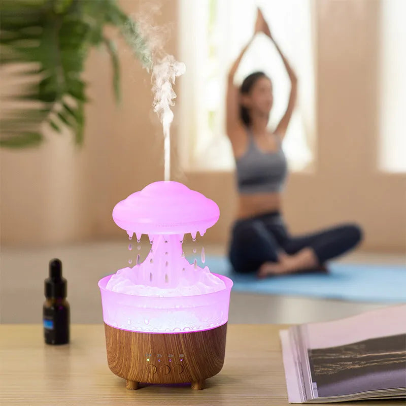 Wood grain white cloud-shaped humidifier diffuser with LED lights and water drop rain effect on a table.