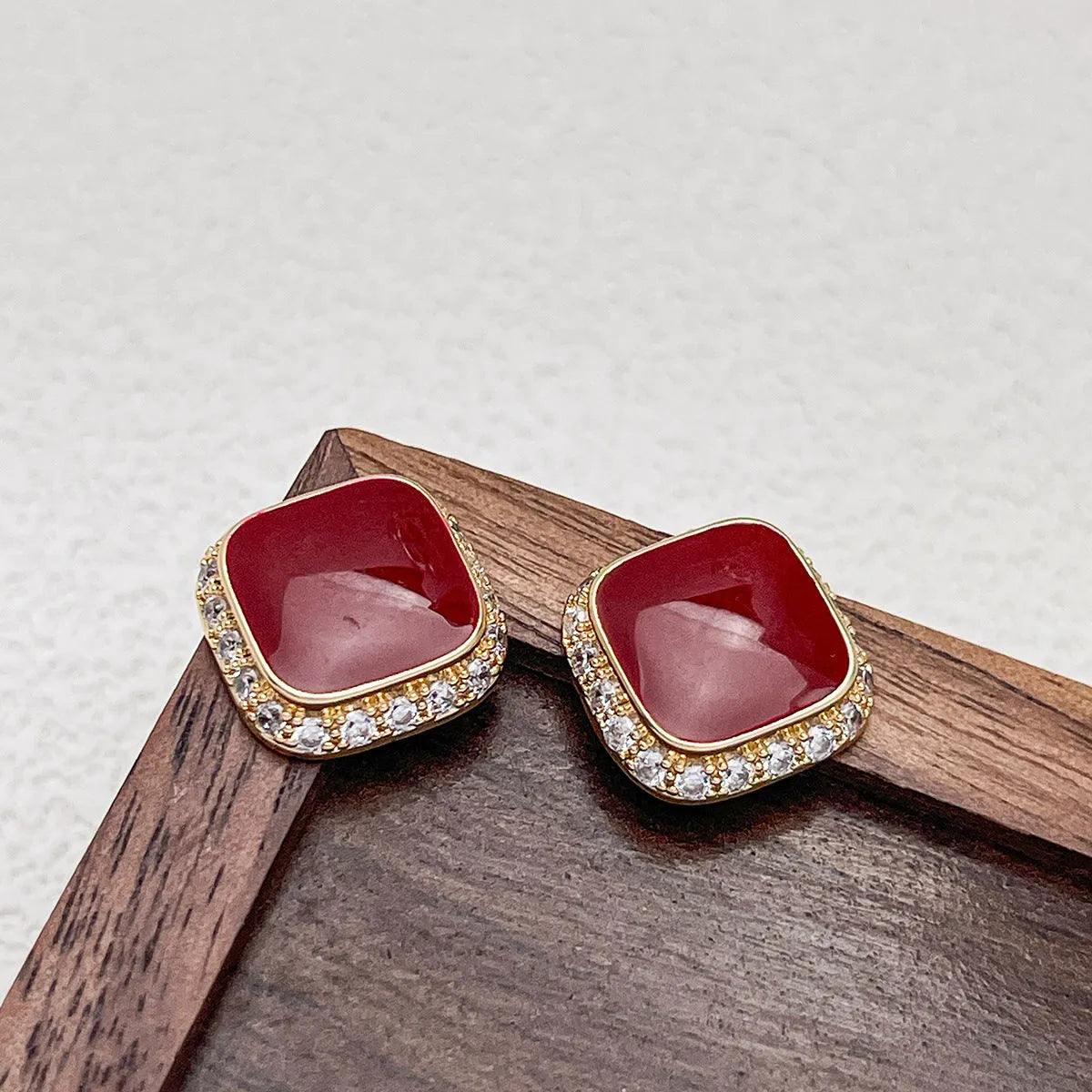 Red alloy square earrings with an inlaid geometric pattern, shown from the front.