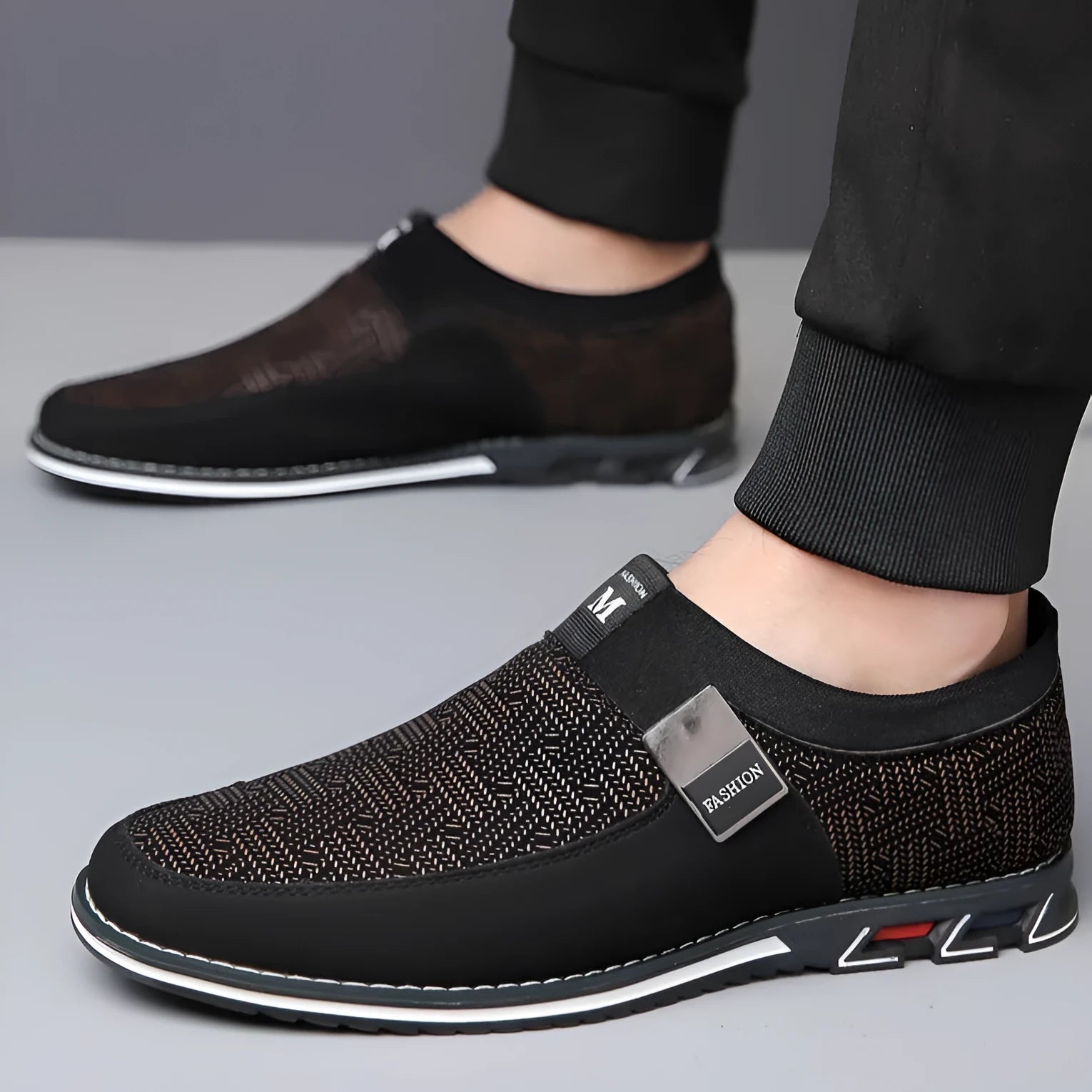 Men's synthetic leather slip-on casual shoe in black, showing square toe and flat rubber sole.