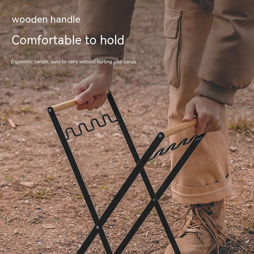 Black iron folding bin rack with wooden handles holding two rubbish bags in an outdoor setting.