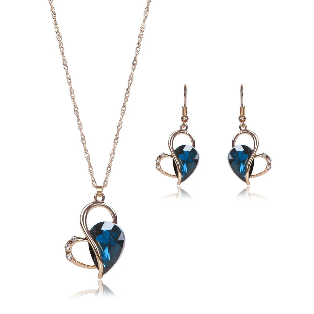 Rose gold two-piece jewellery set with heart pendant, water wave chain necklace, and earrings on display