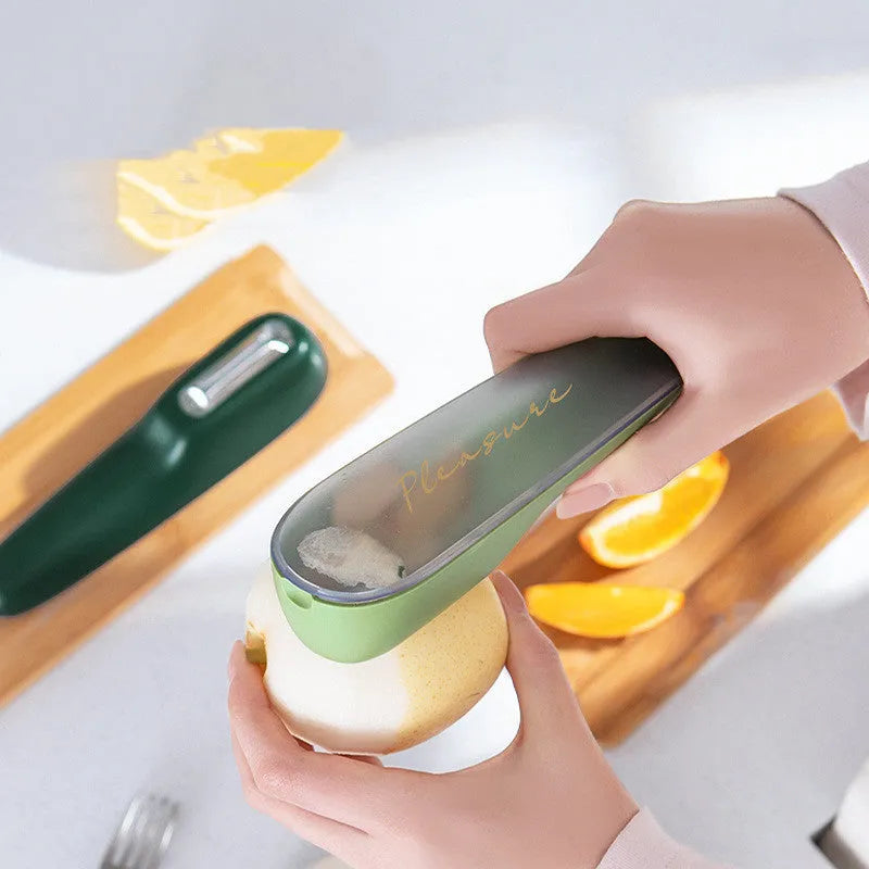 Green vegetable peeler with a storage tube, stainless steel blade, and plastic handle on a kitchen worktop.