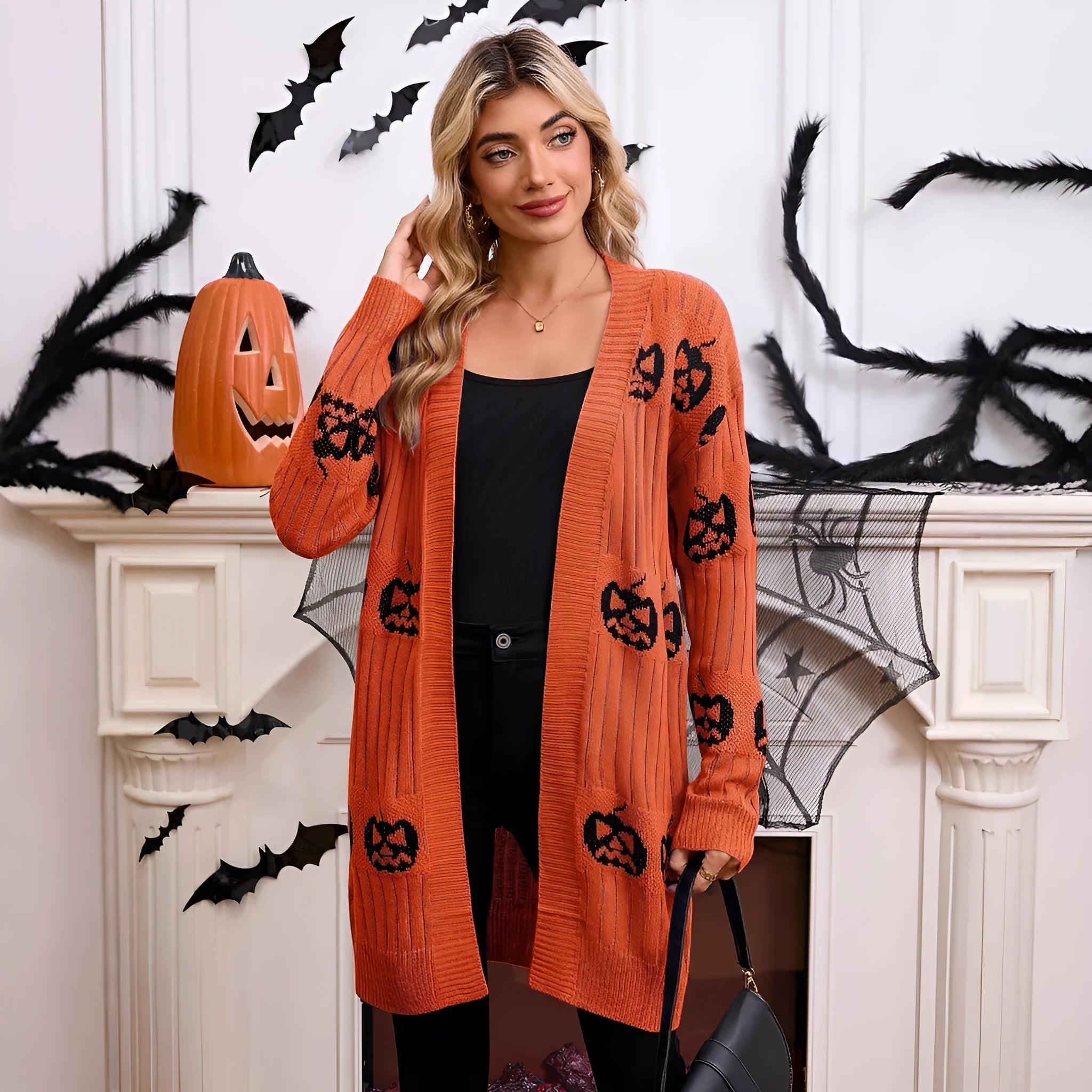 Women's black Halloween cardigan with orange Jacquard knitted pumpkin head pattern, shown as an open medium-length knit.