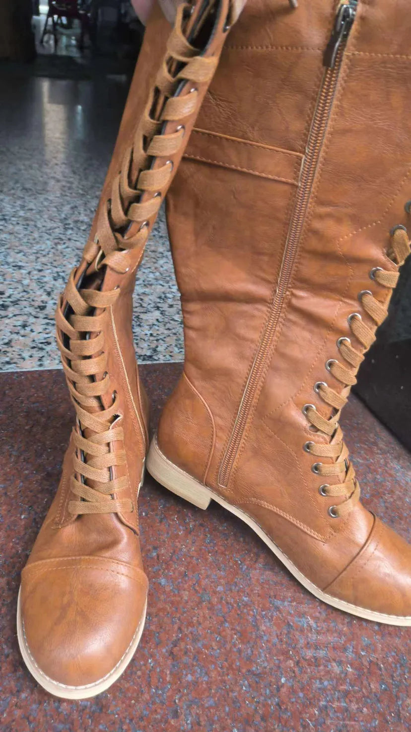 Women's black artificial PU leather knight boots with a cross-strap design, shown from the side.