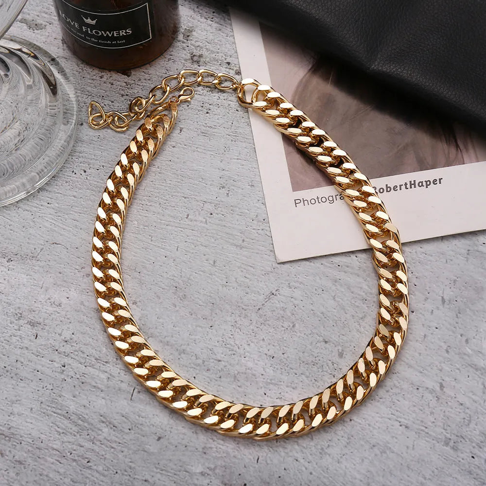 Gold-coloured thick chain necklace for women on a plain background