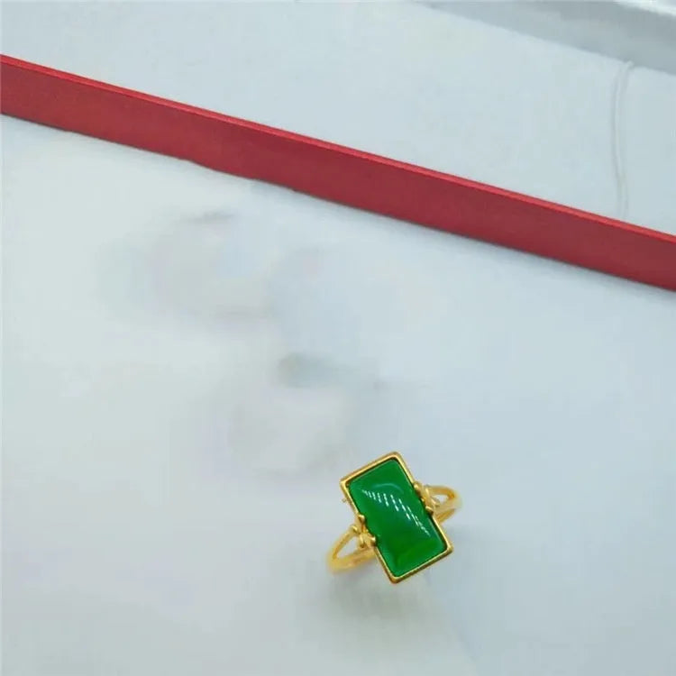 A gold-coloured adjustable ring with a large central green artificial gemstone, showing the national style design.