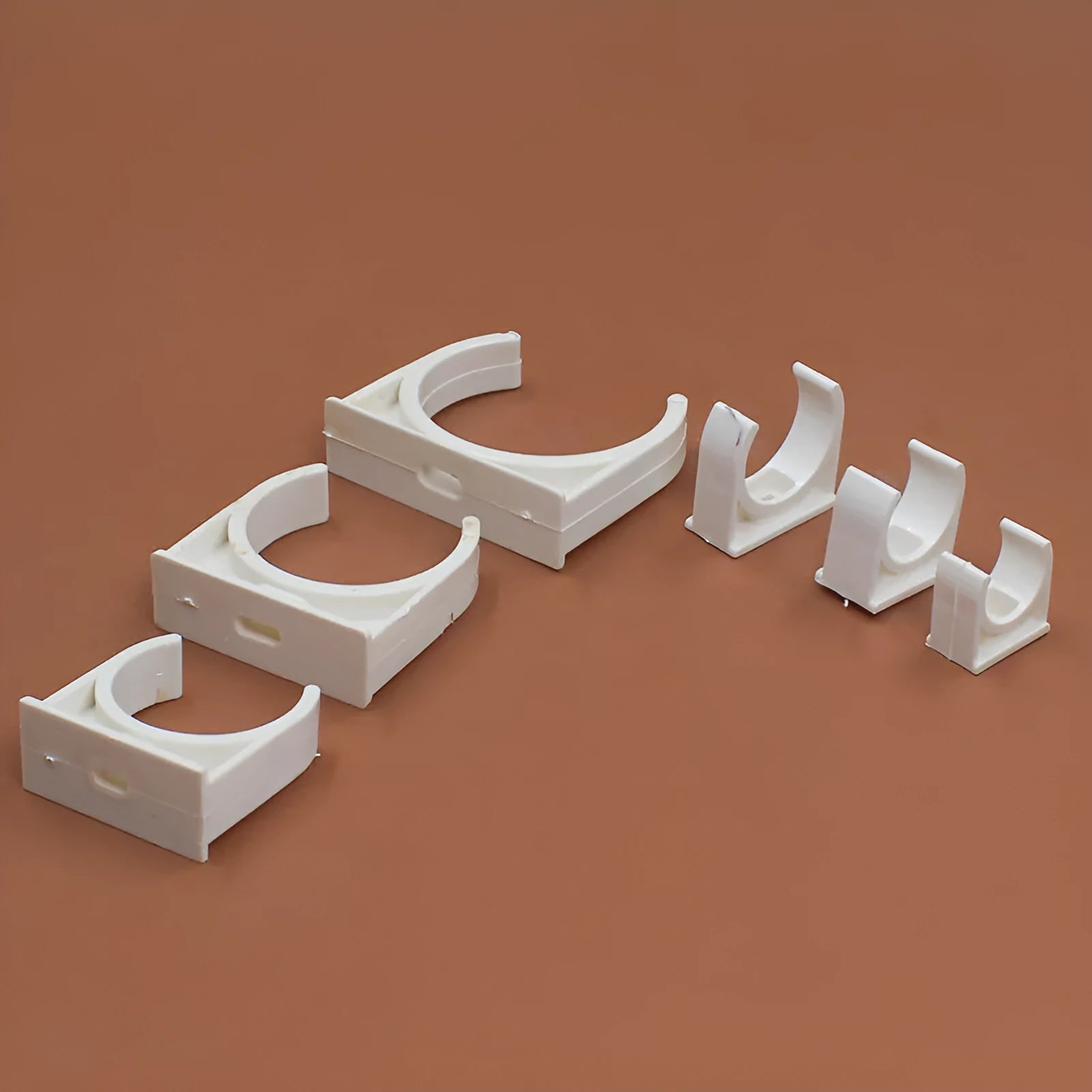 Pack of PVC U-shaped pipe clamps in various sizes for pipe routing