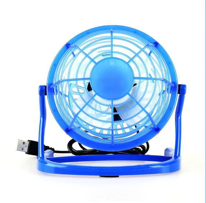 Mini black USB desk fan with adjustable tilt, shown on a desk next to a laptop.