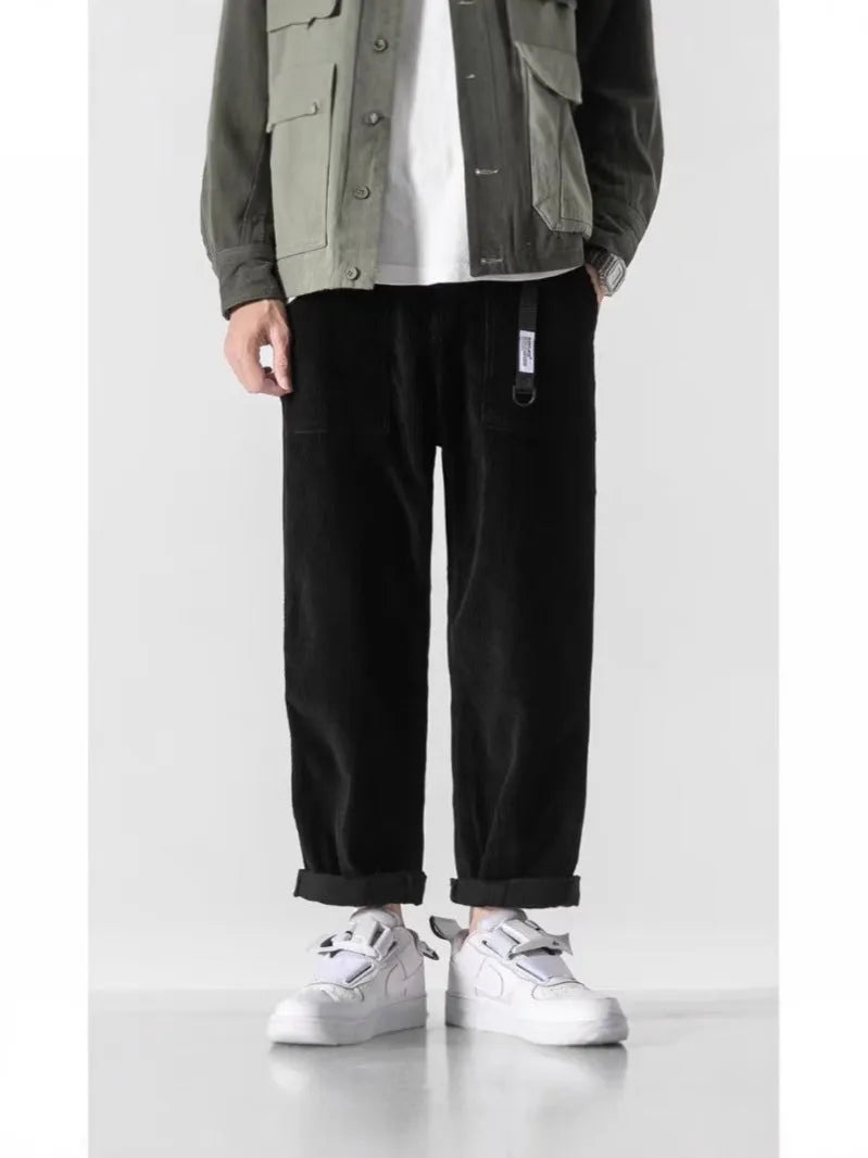 Man wearing loose straight-leg tapered trousers in dark grey, showing the full length and relaxed fit.