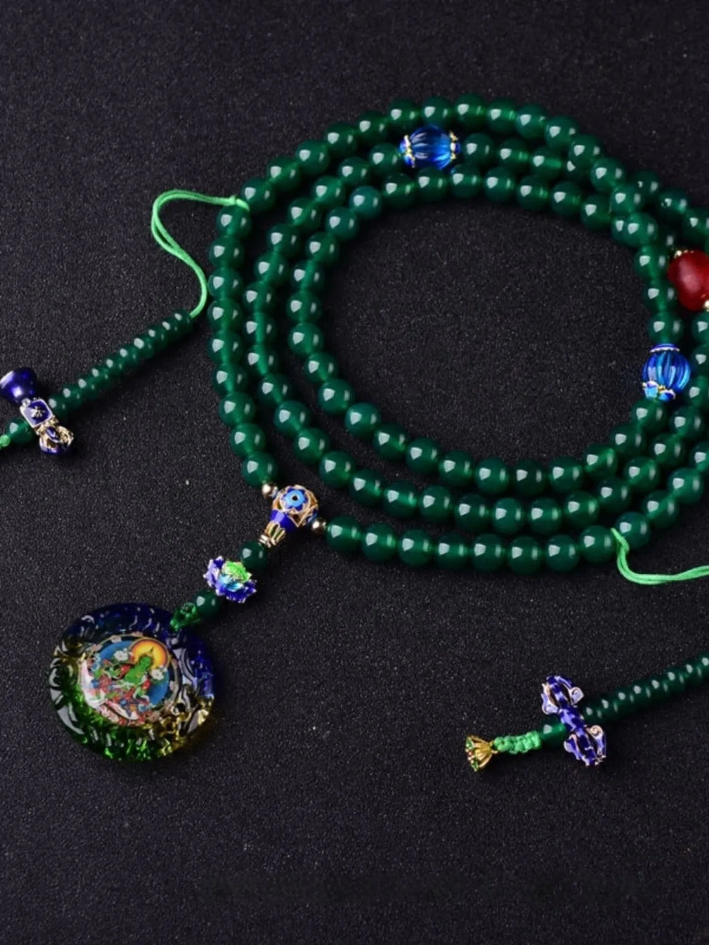 Handmade natural green agate 108 bead bracelet with thangka pendant on a wrist.