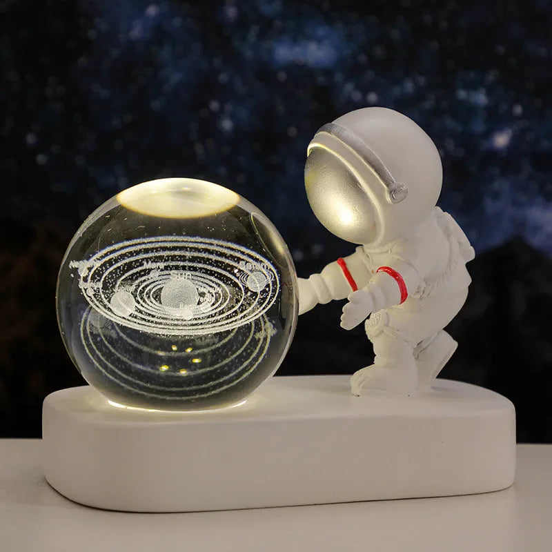 Small clear resin ball night light with glowing astronaut and galaxy scene inside on dark surface