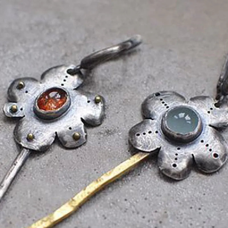 A pair of long retro-style earrings with a geometric floral shape in an asymmetric two-tone colour finish.
