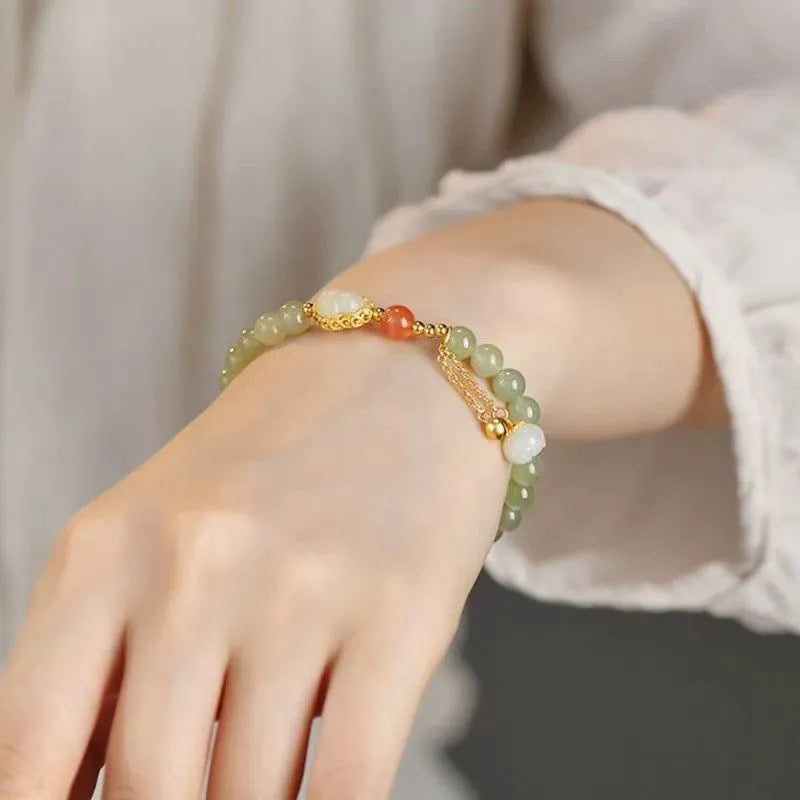 Natural jade bracelet with a gold-plated gourd charm and fu character charm.