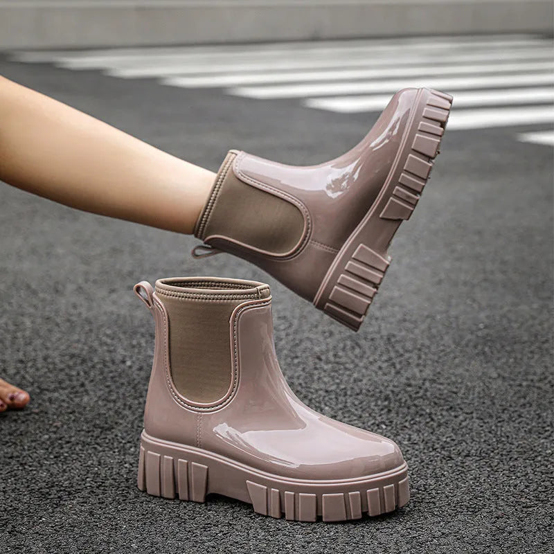 Women's creamy-white PVC rain boots with low tube shaft and flat heel on wet surface