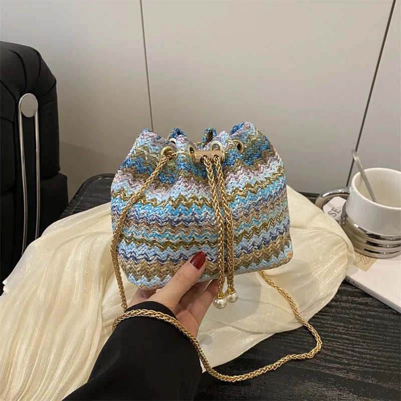 Multicolor straw weave bucket bag with plaid pattern, chain strap, and diamond embellishments