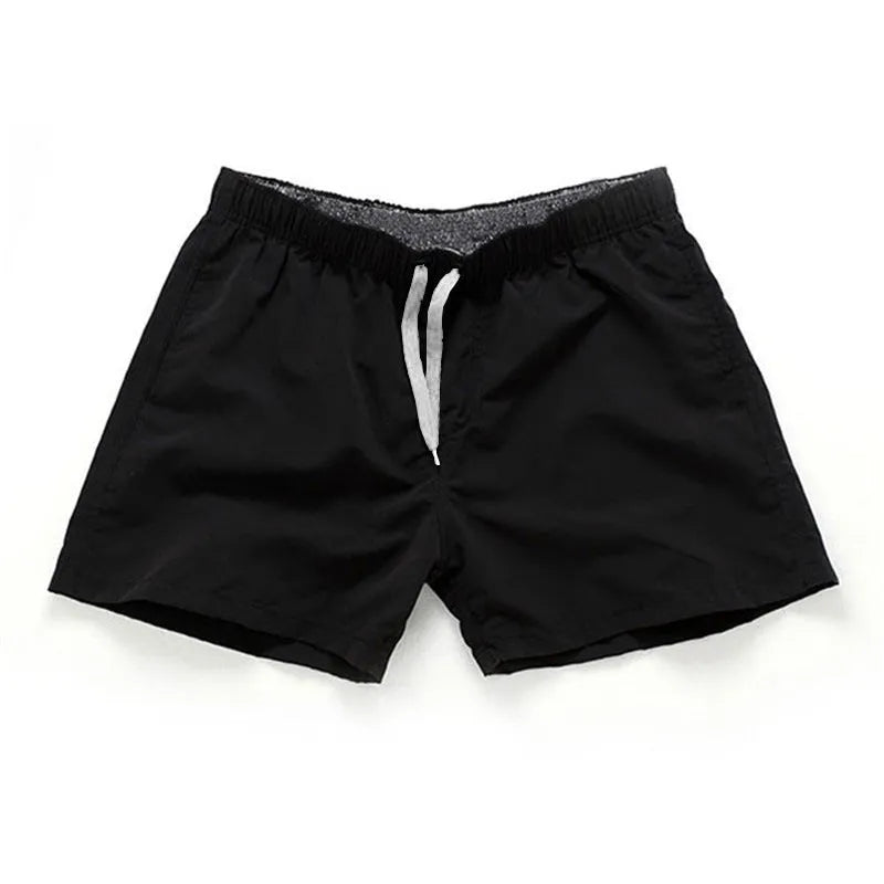 Men's straight-leg polyester surf shorts on a beach, available in multiple colours including fluorescent yellow and black.