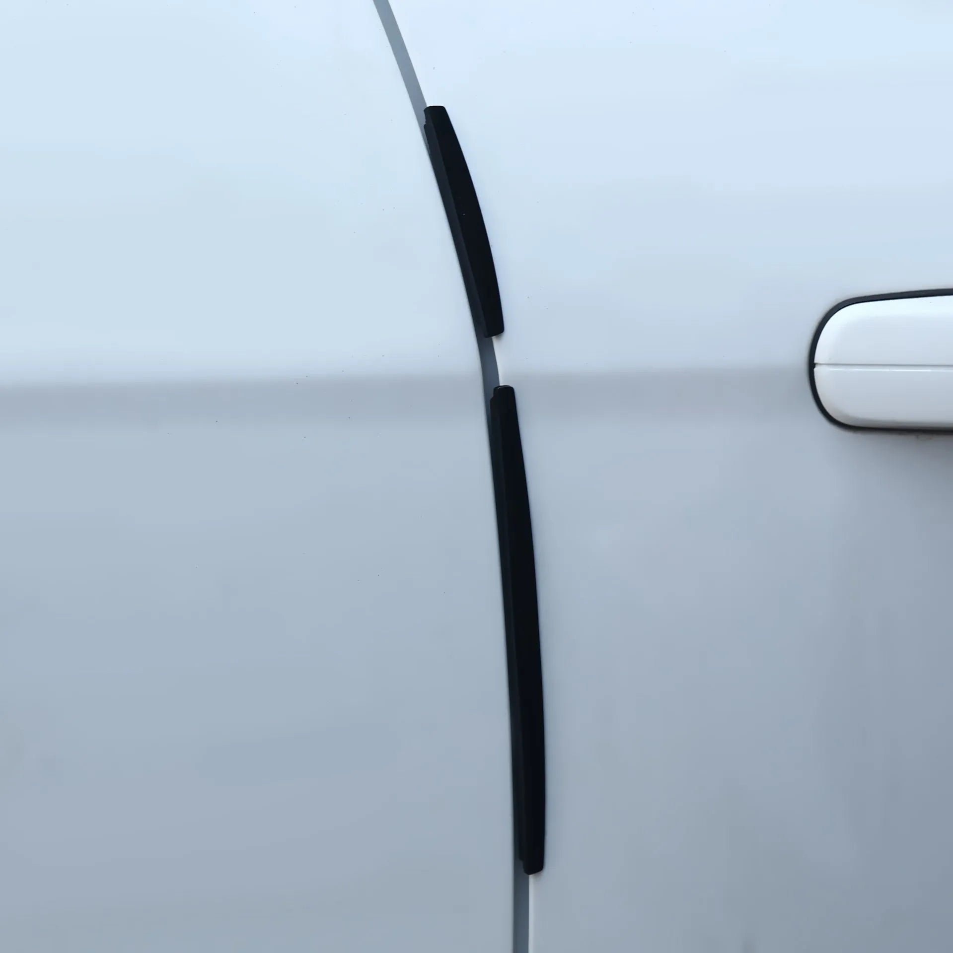 White plastic car door edge protection bumper strip on a vehicle door.