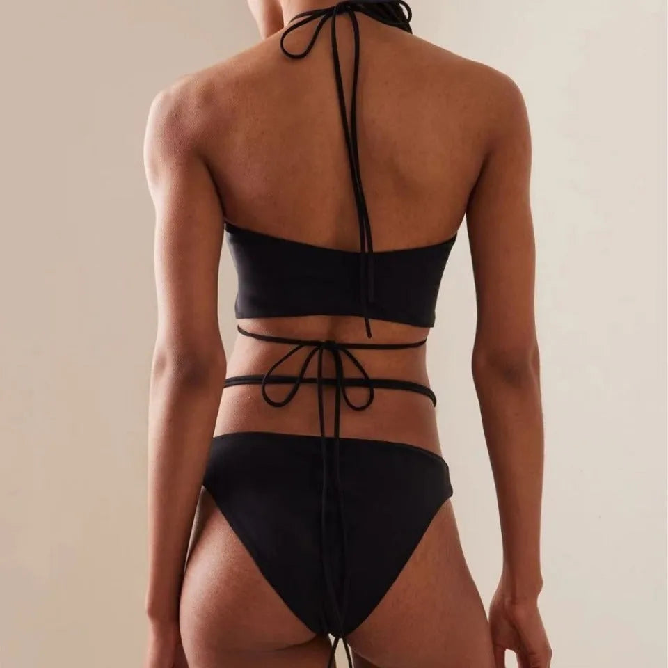 Women's black split lace-up bikini swimsuit with brief shorts and sleeveless bra top.
