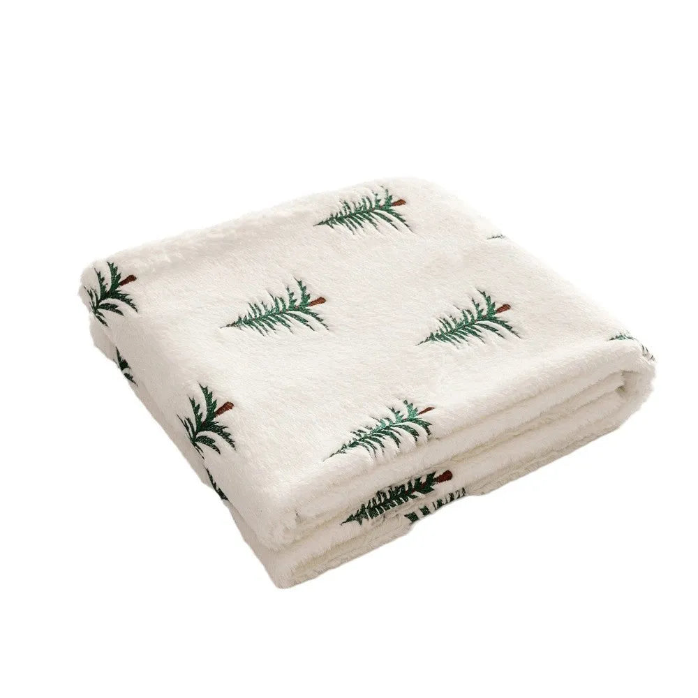 White Christmas plush sofa blanket with embroidered tree motif on a living room sofa