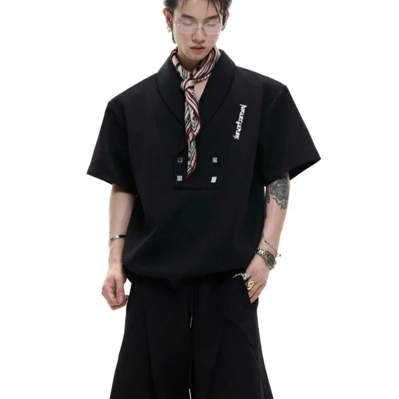 Men's dark grey v-neck sports jacket with padded shoulders and metal details, worn with matching shorts.