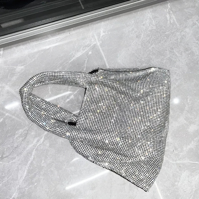 Silver cotton thread evening clutch covered in shiny rhinestones with an open outer pocket and shoulder strap.