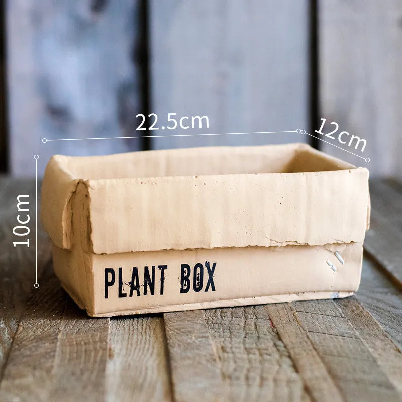 Cement flowerpot with brown paper carton design and drainage hole for indoor balcony plants.