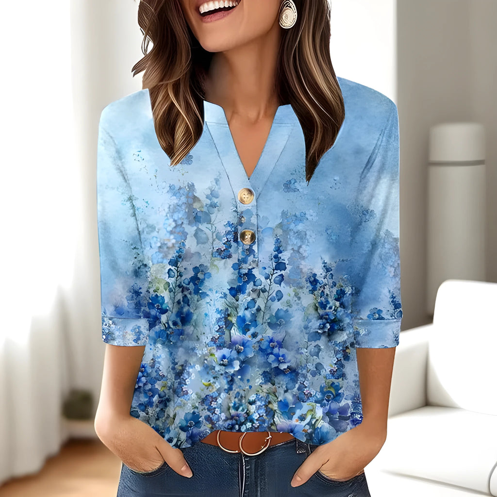 Women's loose-fit V-neck top with a colourful 3D effect pattern, shown in a casual setting.
