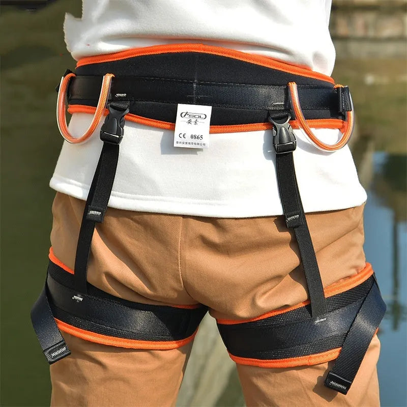 Orange half seat belt climbing safety belt with adjustable waist and leg straps on outdoor rock background