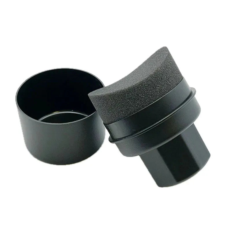 Hand-held black tyre oil sponge brush with lid on a white background.
