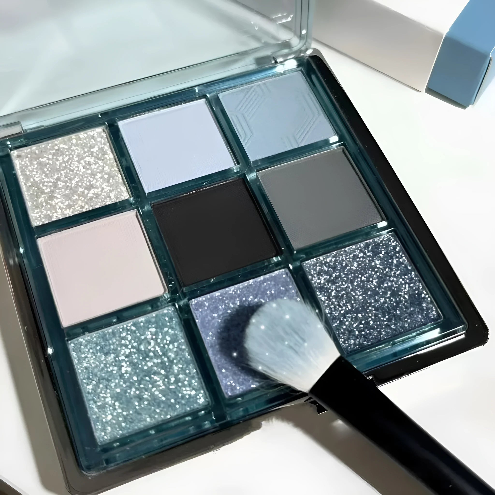MUGELEEN nine-colour eye shadow palette open showing blue smoked and earth tone shades with matte and shimmer finishes.