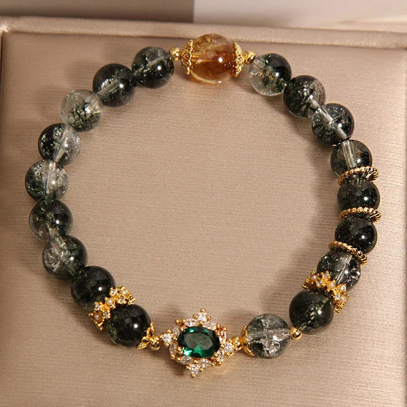 Women's gold rutilated quartz crystal bracelet with green phantom quartz accents, pearls, and rhinestones.